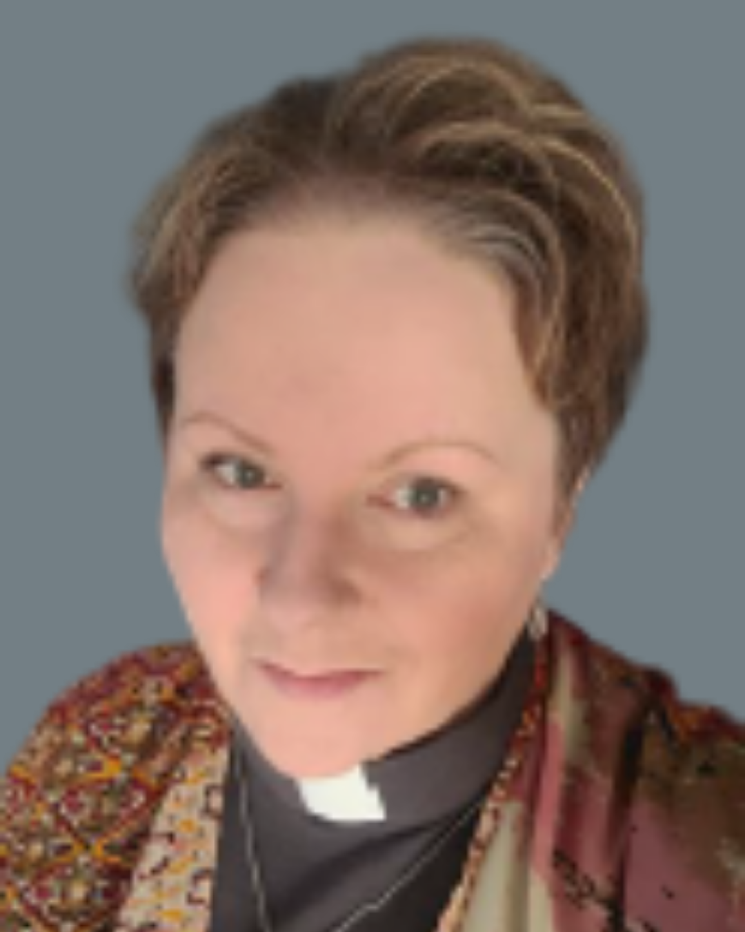 Susan Smandych Board member a white middle aged woman with short brown hair wearing a dark top with a clerical collar and having a brown patterned scarf as a jacket