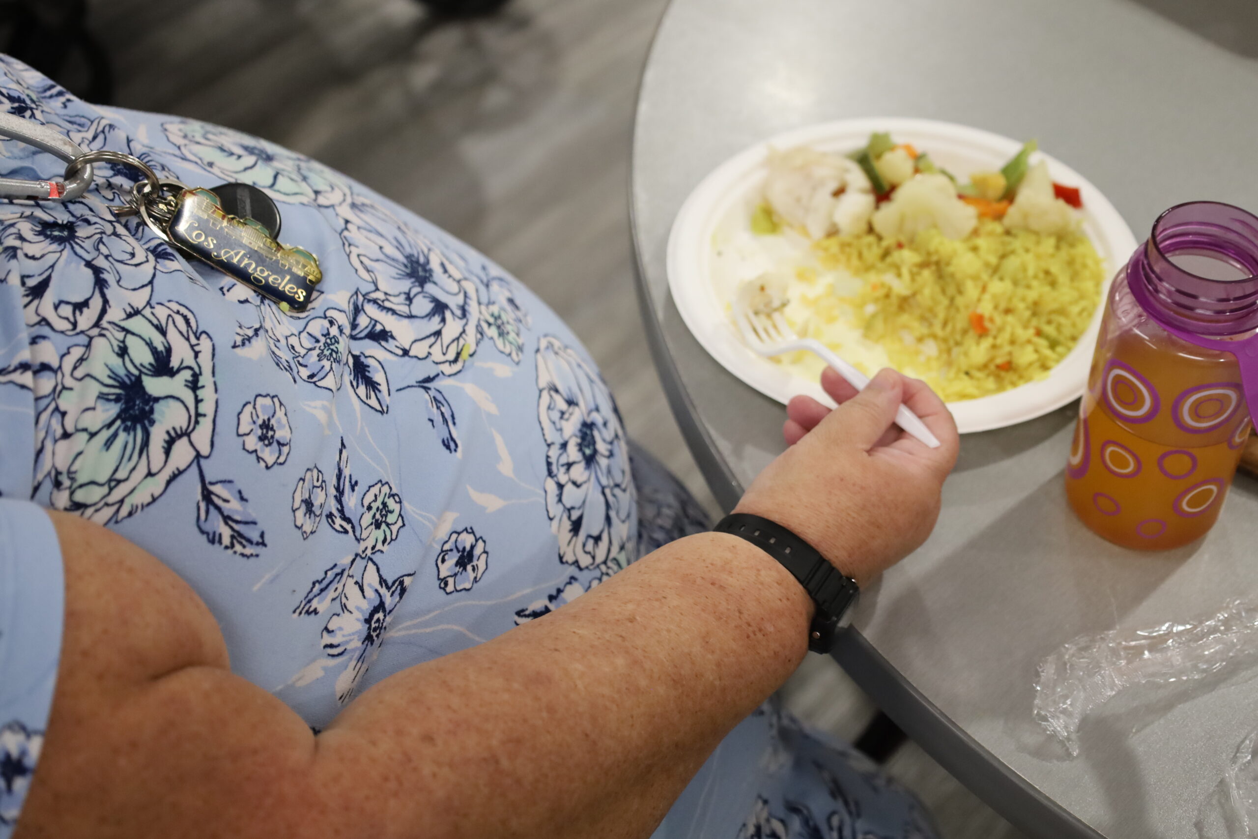 Image of the side of a woman with a plate of food on her table